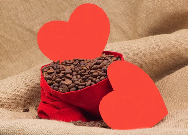 Two red paper hearts with coffe beans in red velvet sac — Stock Photo, Image