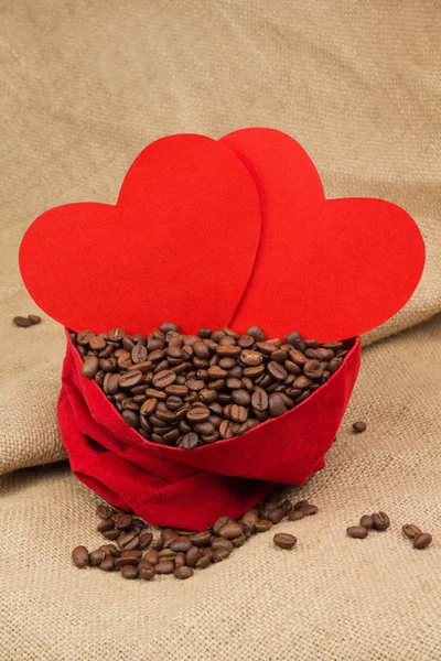 Coffe beans in red velvet sac with two red hearts — Stock Photo, Image