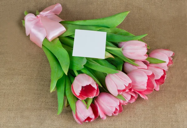 Un bouquet de tulipes roses avec ruban de satin et petite carte postale — Photo