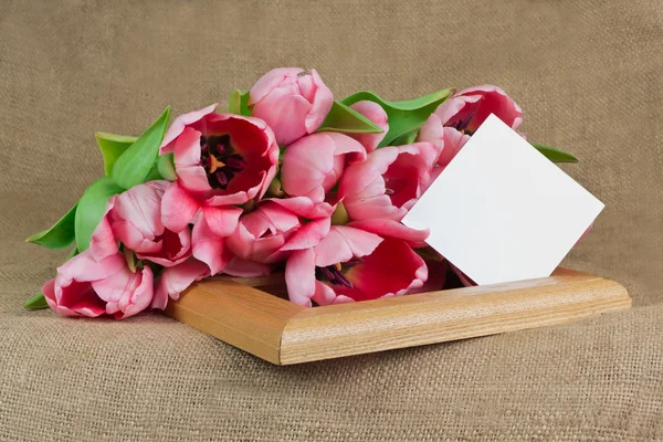 Varios tulipanes rosados con una pequeña postal sobre el marco — Foto de Stock