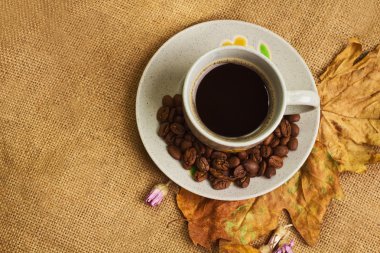 Akçaağaç yaprakları ve sonsuz çiçekleri ile kahve fincan