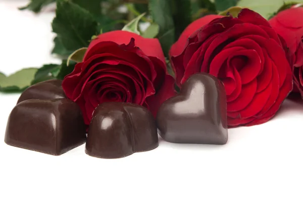 Roses rouges et bonbons en forme de coeur isolé — Photo