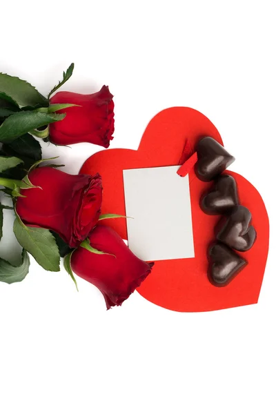 Strauß roter Rosen, zwei rote Papierherzen und Bonbons — Stockfoto