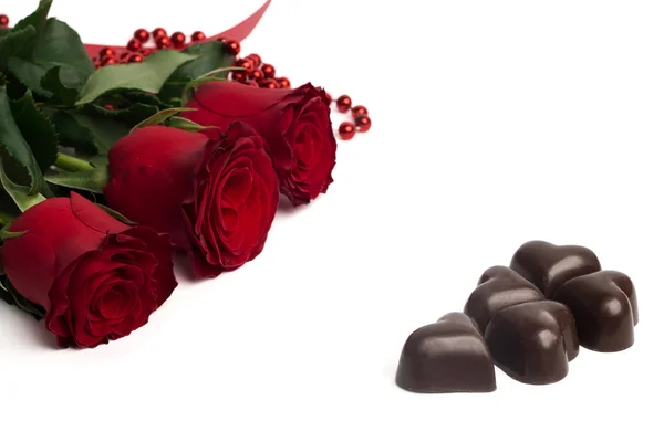 Roses rouges et bonbons en forme de coeur isolé — Photo