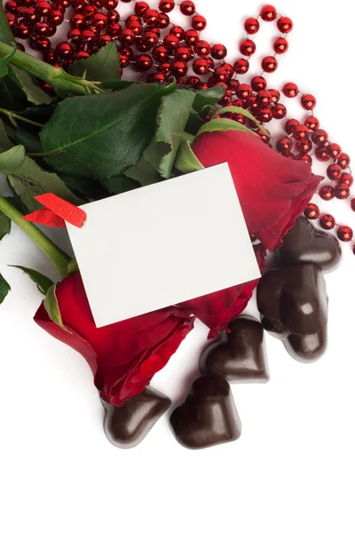 Czerwone róże i cukierki w kształcie serca na białym tle — Zdjęcie stockowe