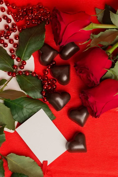 Röda rosor och godis i en form av ett hjärta — Stockfoto