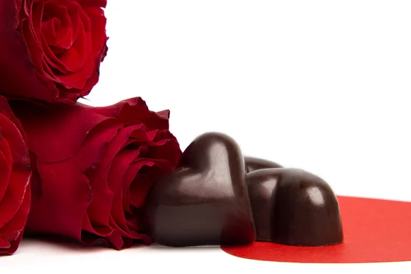 Roses rouges et bonbons en forme de coeur isolé — Photo