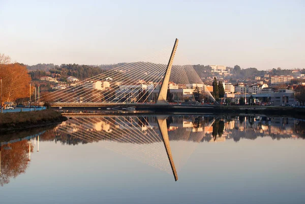 Reflection of bridge and houses form mirror effect in the river. Galicia, Spain