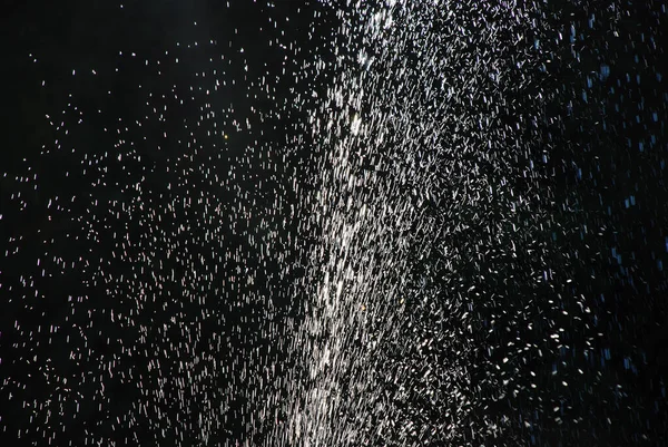 Jet of water splashing with pressure with detail of the drops on a black background.