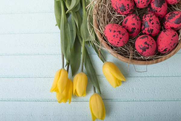 Fundo de Páscoa com ovos vermelhos e tulipas amarelas — Fotografia de Stock