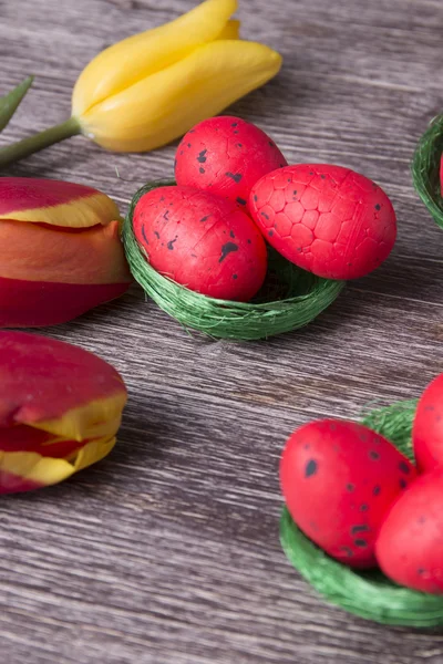 Ovos de Páscoa vermelhos no ninho verde e tulipas coloridas — Fotografia de Stock