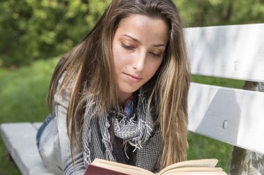 genç kadın bir parkta bankta bir kitap okuma