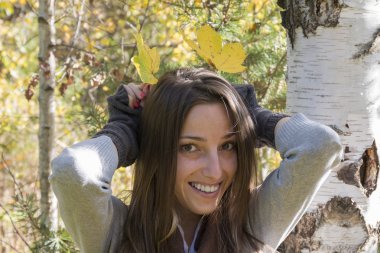 Genç kadın sonbahar yaprakları ile eğleniyor