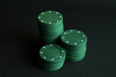 Siyah arka planda üç deste yeşil poker fişi.