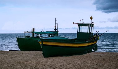 Kumlu kıyıya demir atmış iki tekne. Yaz zamanı ve deniz kıyısında.