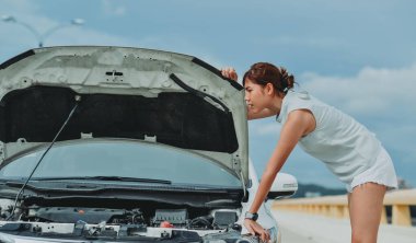 Kaputu patlamış, bozuk bir arabanın yanında duran genç bir kadın aracıyla sorun yaşıyor. Otomatik arıza dışında yardım bekleyen kadın sürücü.