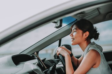 Çekici Asyalı kadınlar araba sürerken gülümsüyor ve dik dik bakıyor. Seyahat tatili. Rahatlamak ve eğlenmek..