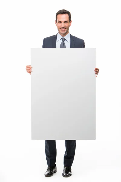 Full length portrait of a smiling businessman holding a white placard — Stock Photo, Image