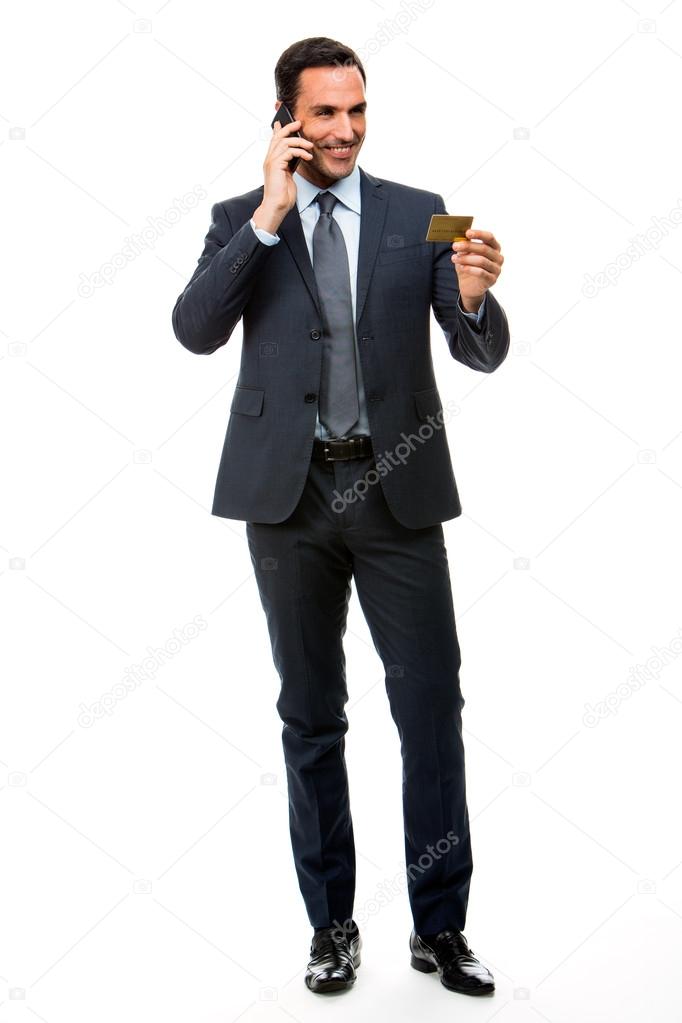 Full length portrait of smiling businessman on the phone holding a credit card