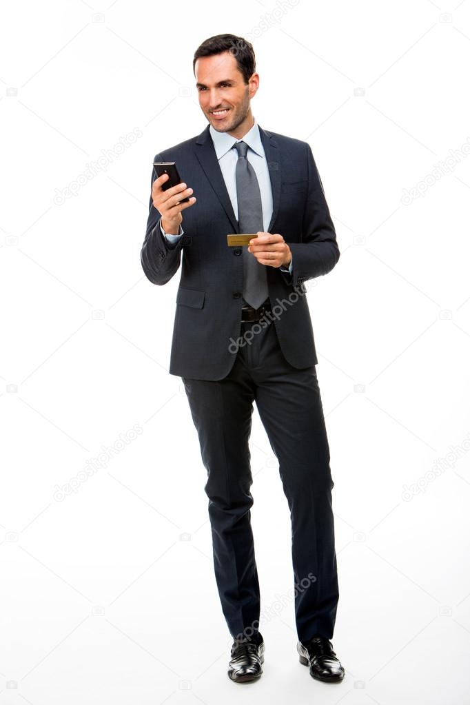 Full length portrait of a smiling businessman holding mobile phone and credit card
