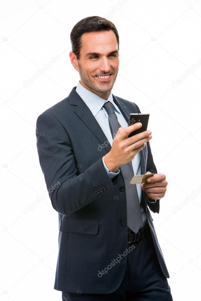 Half length portrait of a smiling businessman holding mobile phone and credit card