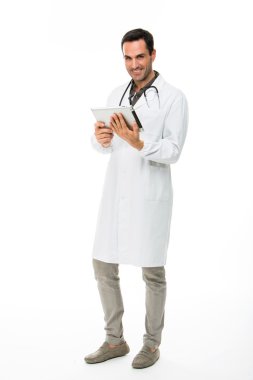 Tam uzunlukta portre os dijital tabletiyle çalışırken stetoskop ile gülümseyen bir erkek doktor