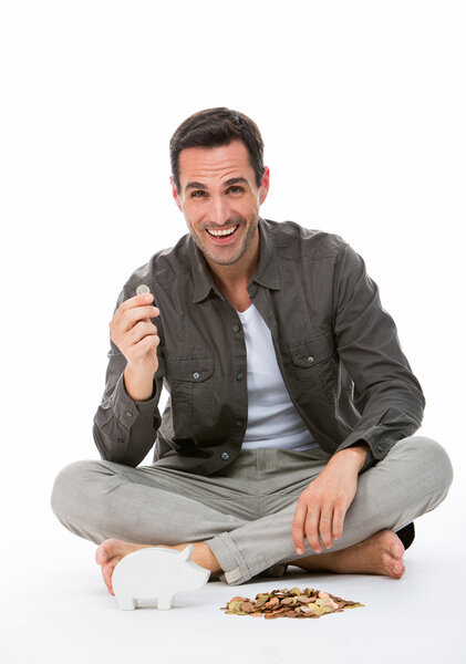Man sitted on the floor, smiling at camera, holding a coin