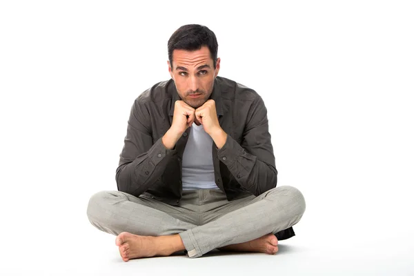 Задумчивый мужчина сидел на полу с руками под подбородком — стоковое фото