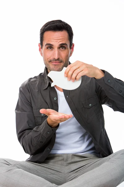 Man sitted on the floor, looking at camera and showing an empty piggybank — Stock Photo, Image