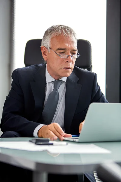 Portrait à mi-longueur d'un homme d'affaires réfléchi dans le bureau tout en utilisant un ordinateur portable — Photo