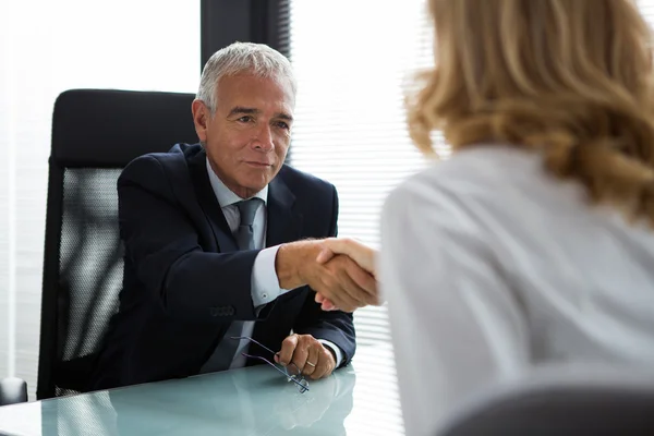 Two businesspeople, male and female, shaking hands during a meeting in the office — Stock Photo, Image