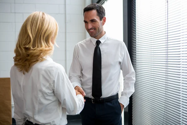 Retrato de medio cuerpo de dos empresarios de pie, sonriendo y dándose la mano — Foto de Stock