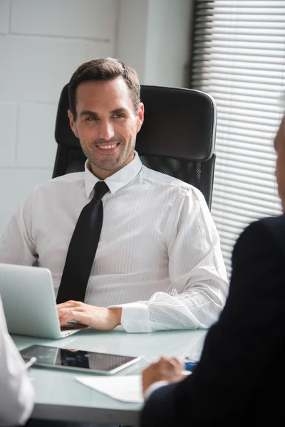 Três empresários que têm uma reunião no escritório com um computador portátil e um tablet digital — Fotografia de Stock