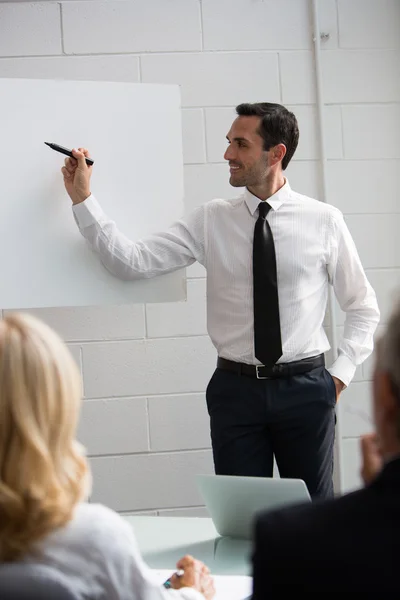 Tre uomini d'affari durante una riunione, un manager che scrive su un cartellone bianco — Foto Stock