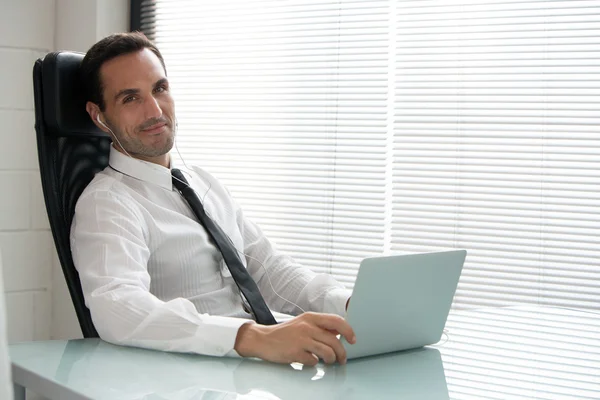 Businessman with earphones and laptop computer — Stock Photo, Image