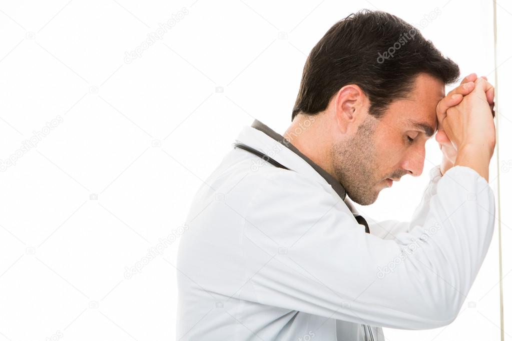 Half length profile portrait of a thoughtful male doctor his head leaning to the hands