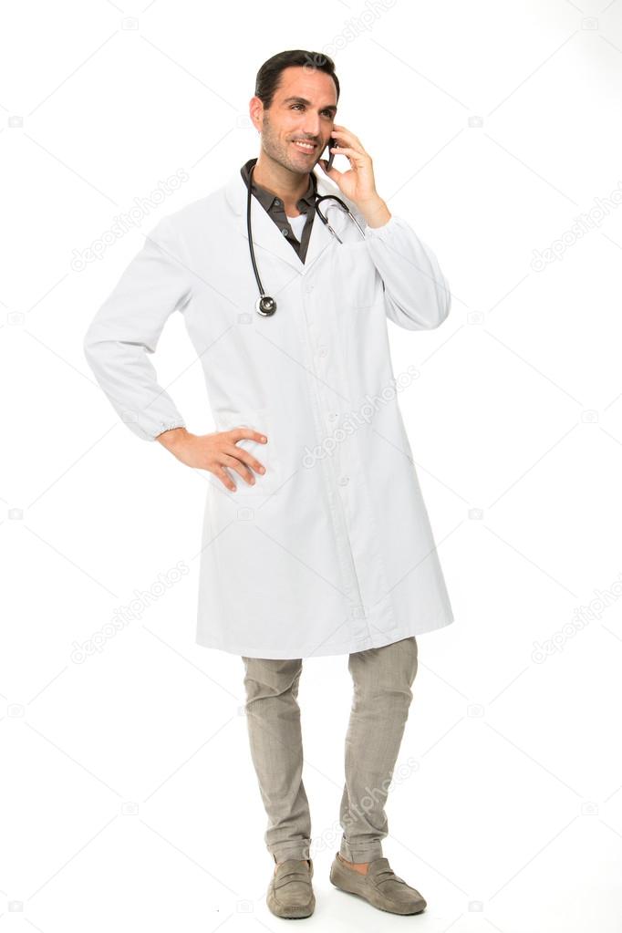 Full length portrait os a smiling male doctor with stethoscope while using a mobile phone