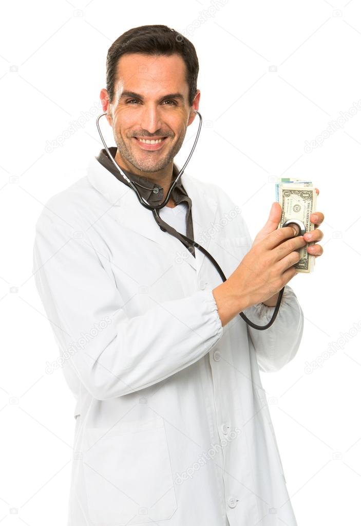 Half length portrait of a male doctor, smiling at camera and using stethoscope on money