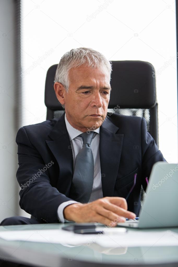 Half length portrait of a thoughtful businessman in the office while using laptop computer