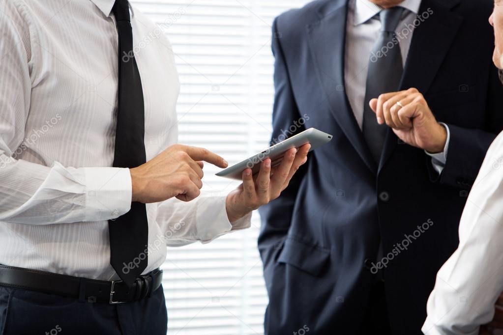 Half lenght portrait of two businessmen talking and using a digital tablet