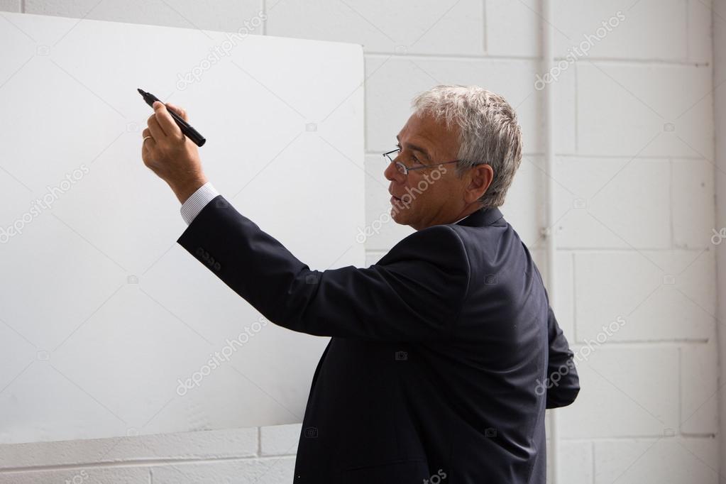 Half length portrait of a businessman wrtiting on a blank billboard with a black marker