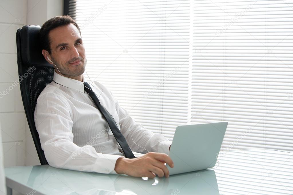 Businessman with earphones and laptop computer