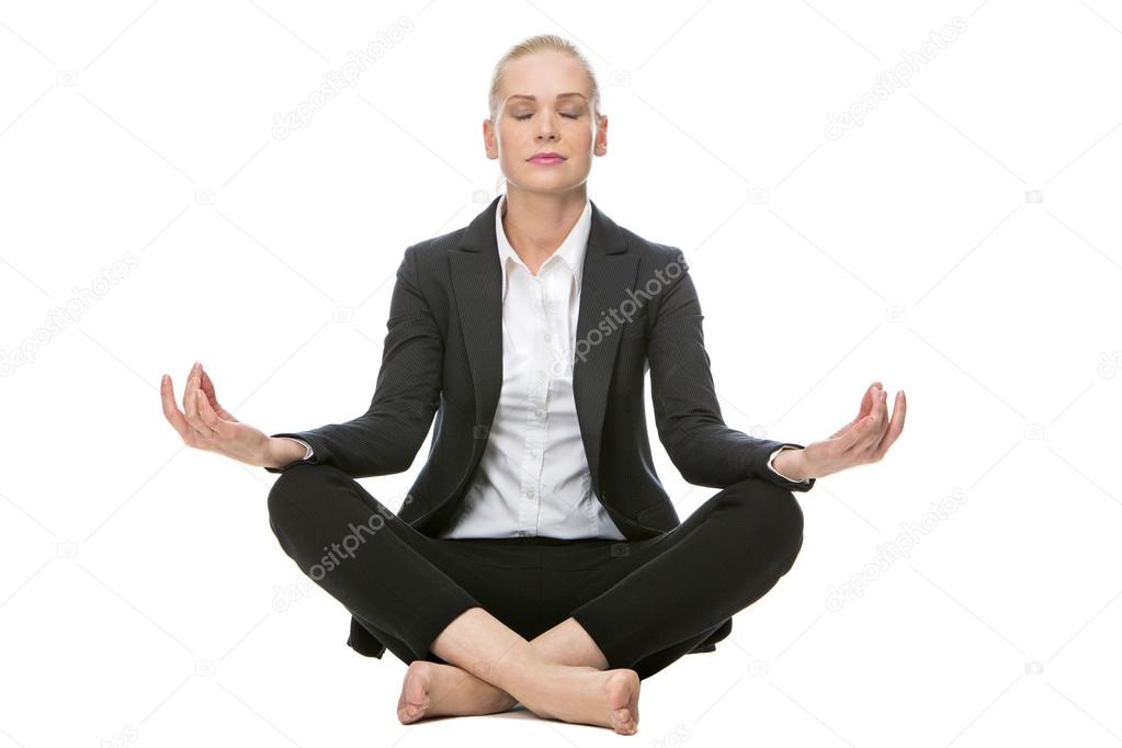 Blonde businesswoman seated on the floor doing a yoga position with her eyes closed