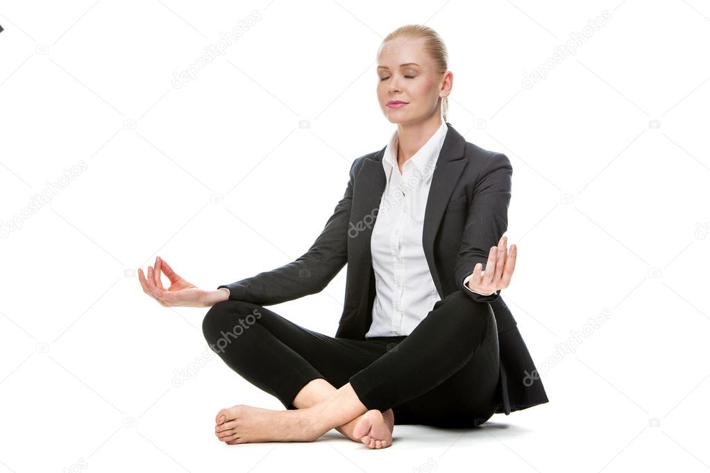 Blonde businesswoman sitted on the floor doing a yoga position with her eyes closed