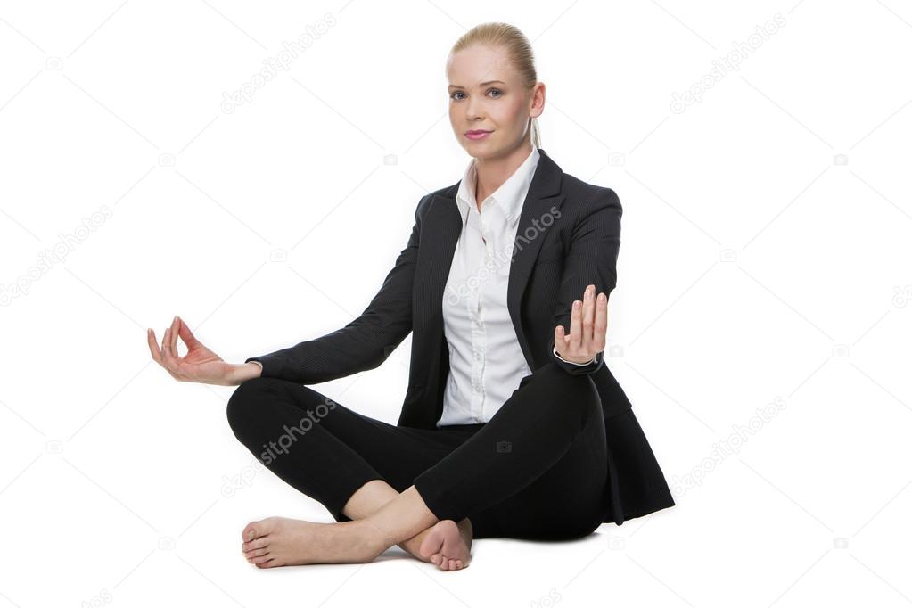 Businesswoman seated on the floor doing a yoga position