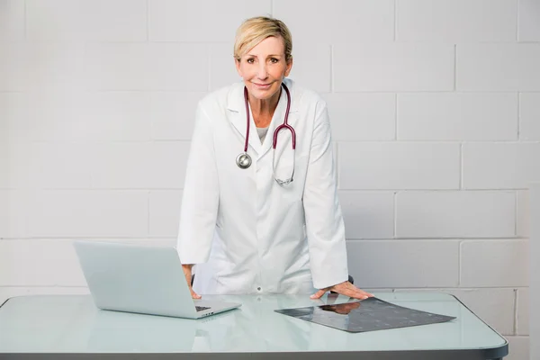 Femme médecin debout derrière le bureau — Photo