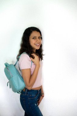 Okul çantası ve beyaz bir geçmişi olan küçük bir kız.