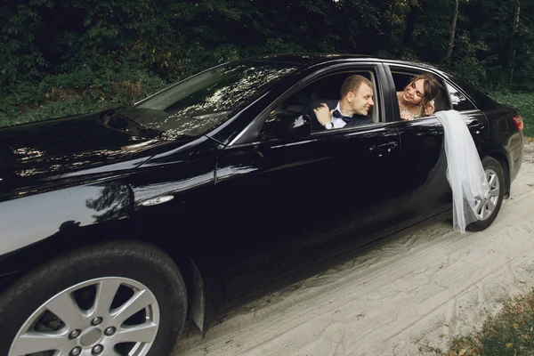 Noiva e noivo dirigindo em carro de luxo — Fotografia de Stock