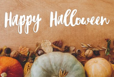 Cadılar Bayramı 'nda balkabağı, sonbahar yaprakları, fındık ve baharatlar üzerine Mutlu Cadılar Bayramı metinleri. El yazısı, mevsimlik tebrik kartı.