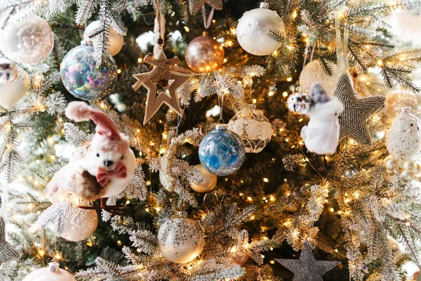 Şenlik odasında gümüş takılar ve altın ışıklarla süslü bir Noel ağacı. Beyaz topları, gümüş yıldızları ve oyuncakları olan modern Noel ağacı. Mutlu Noeller ve mutlu tatiller!